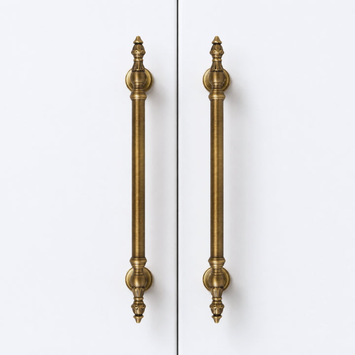 Two long vertical cabinet handles in an antique brass finish, shown side by side against a plain white background.