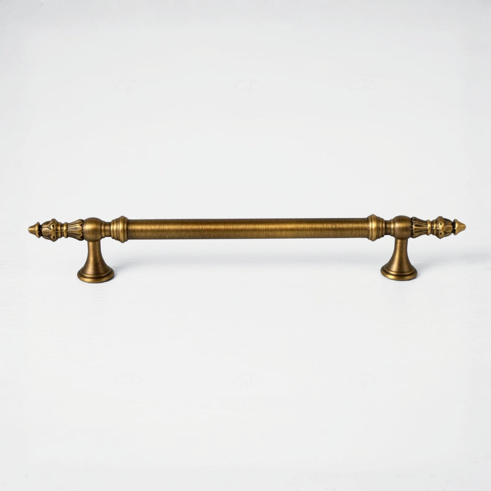 An antique brass cabinet pull handle with ornate turned details and decorative finials on both ends, shown horizontally against a plain white background.