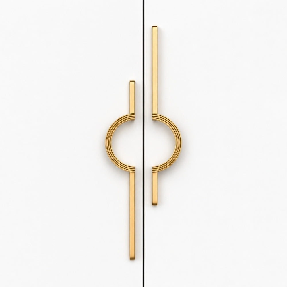 A pair of modern gold cabinet handles with a minimalist circular and linear design, shown on a clean white background split by a vertical seam.